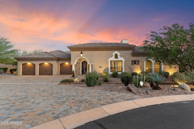 8599 E Sand Flower Dr, Scottsdale, AZ 85266 - mediterranean / spanish home with a tile roof, decorative driveway, a chimney, a garage, and stucco siding