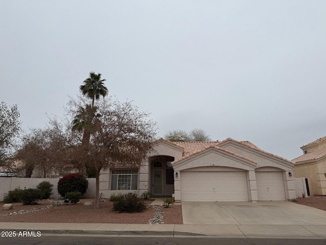 mediterranean / spanish-style house with an attached garage, stucco siding, concrete driveway, and a tiled roof