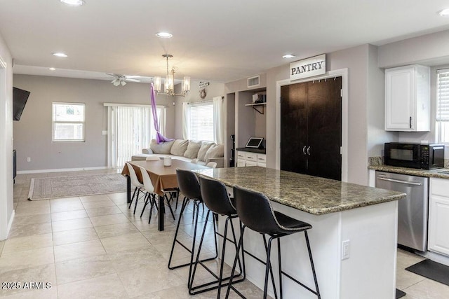 kitchen featuring black microwave, a center island, open floor plan, stainless steel dishwasher, and visible vents