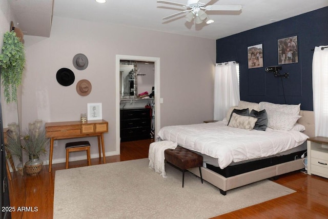 bedroom with a ceiling fan, a closet, wood finished floors, and a spacious closet
