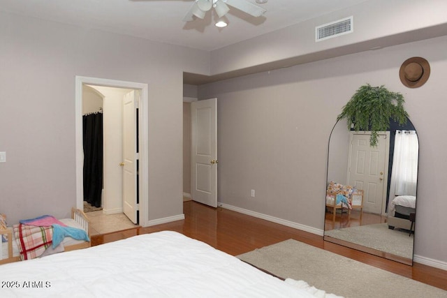 bedroom featuring ceiling fan, baseboards, visible vents, and wood finished floors