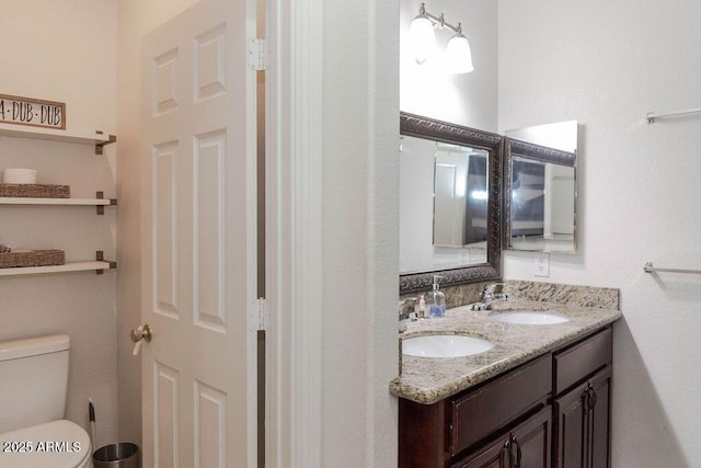 bathroom with double vanity, a sink, and toilet
