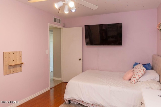 bedroom featuring visible vents, baseboards, ceiling fan, and wood finished floors
