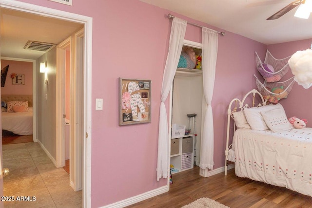 bedroom featuring ceiling fan, visible vents, baseboards, and light wood-style flooring