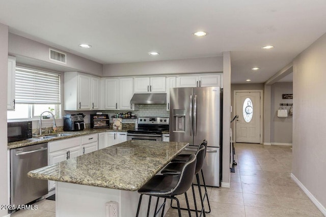 kitchen featuring visible vents, baseboards, under cabinet range hood, a sink, and appliances with stainless steel finishes