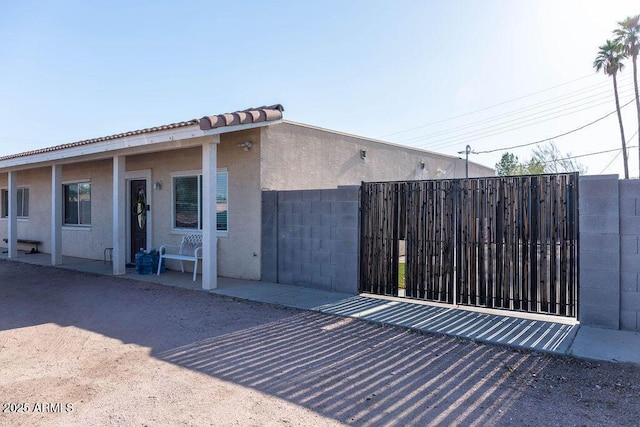 view of side of property featuring fence, a gate, and stucco siding