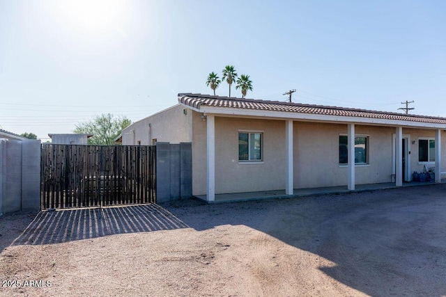 view of home's exterior featuring a tile roof, fence, a gate, and stucco siding