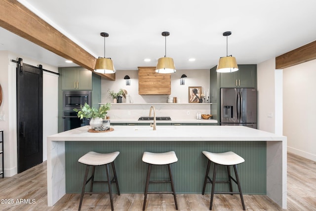 kitchen with a barn door, a breakfast bar area, appliances with stainless steel finishes, light countertops, and green cabinets