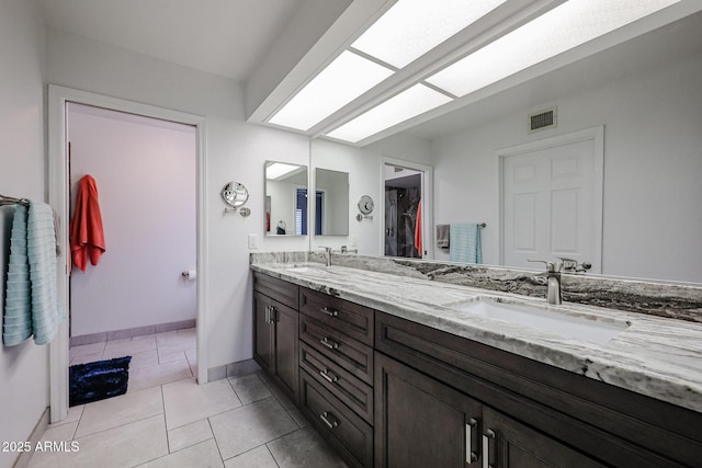 full bath featuring double vanity, a skylight, visible vents, tile patterned flooring, and a sink