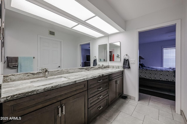 ensuite bathroom featuring a skylight, double vanity, a sink, and ensuite bathroom