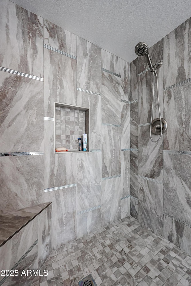 bathroom with tiled shower and a textured ceiling