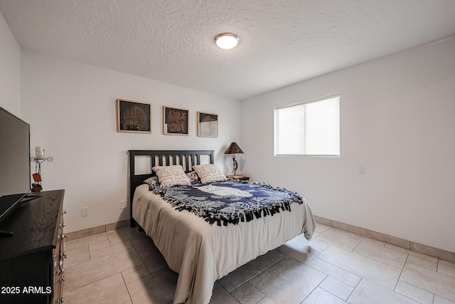 bedroom featuring light tile patterned floors, baseboards, and a textured ceiling