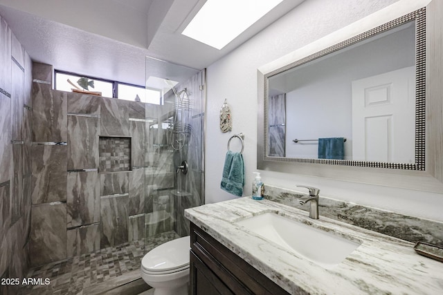 bathroom featuring a tile shower, vanity, and toilet