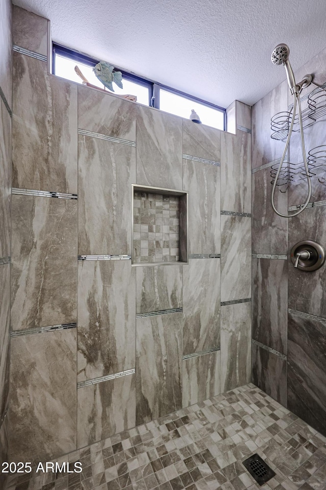 full bathroom featuring a textured ceiling, a tile shower, and a healthy amount of sunlight