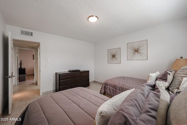 bedroom with baseboards, visible vents, a textured ceiling, and light tile patterned flooring