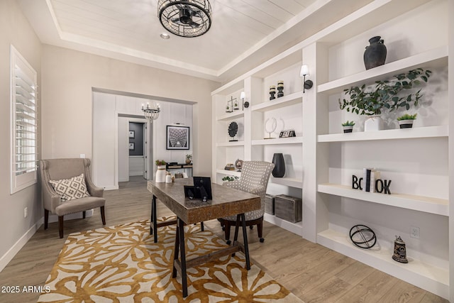 office space featuring a tray ceiling, wood finished floors, and baseboards