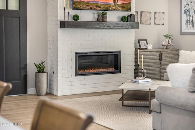 living room with a brick fireplace and wood finished floors