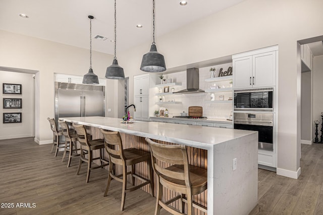 kitchen featuring tasteful backsplash, visible vents, wall chimney range hood, built in appliances, and open shelves