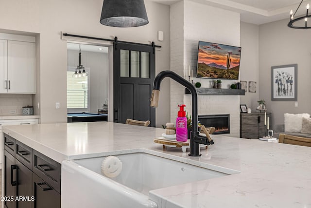 kitchen with a sink, a barn door, open floor plan, and a fireplace