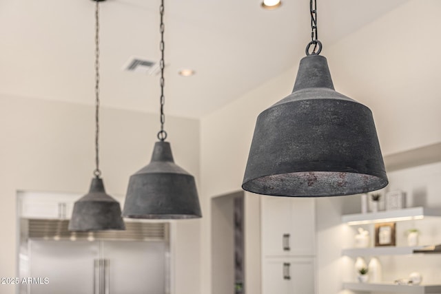 details featuring hanging light fixtures, built in refrigerator, visible vents, and white cabinetry