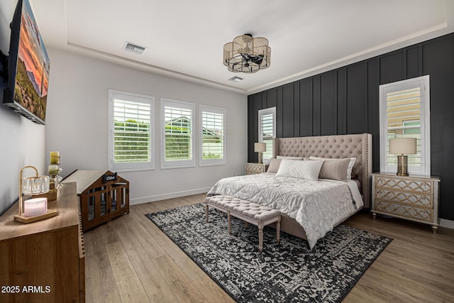 bedroom with wood finished floors, visible vents, and baseboards