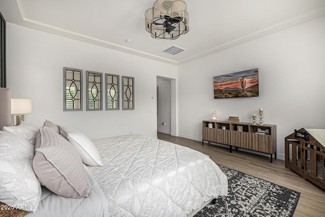 bedroom with visible vents, baseboards, and wood finished floors