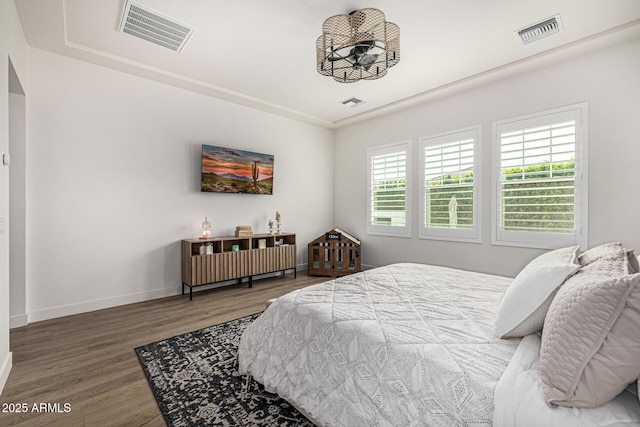 bedroom with visible vents, baseboards, and wood finished floors