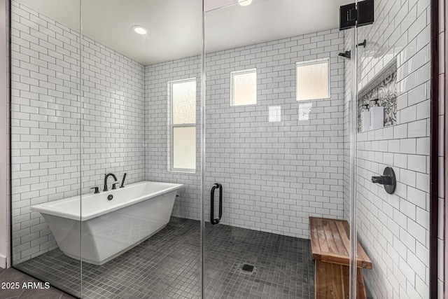 bathroom with tile patterned floors, a shower stall, tile walls, and a freestanding tub