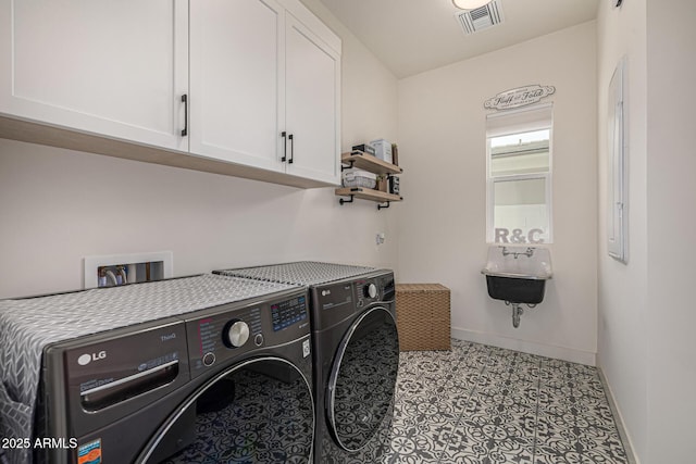 clothes washing area featuring baseboards, cabinet space, visible vents, and washing machine and clothes dryer