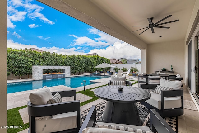 view of swimming pool with outdoor lounge area, a patio area, a fenced backyard, and a ceiling fan