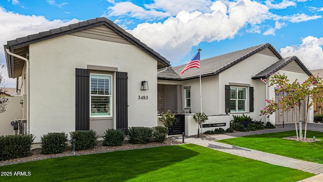 view of front of house with stucco siding, a tiled roof, and a front lawn