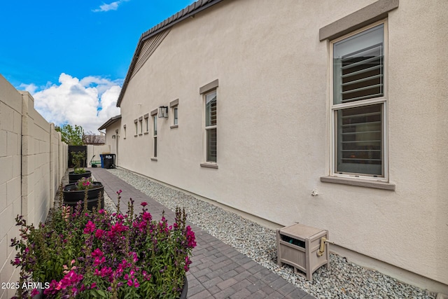 view of side of property featuring a patio area, a fenced backyard, and stucco siding