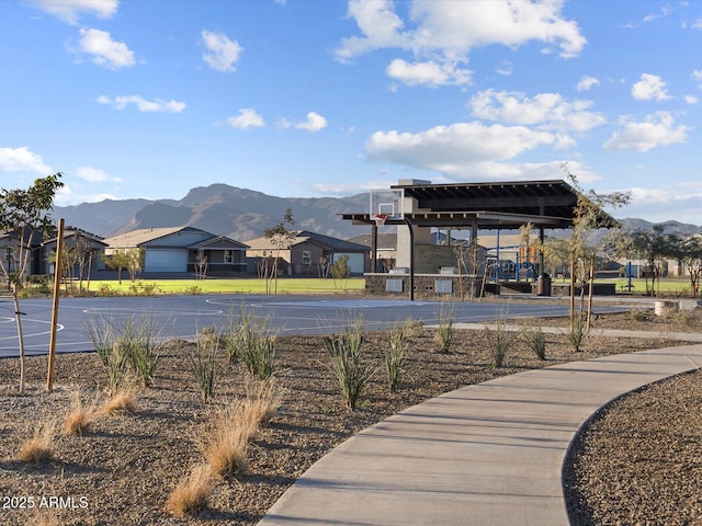 surrounding community with basketball hoop and a mountain view