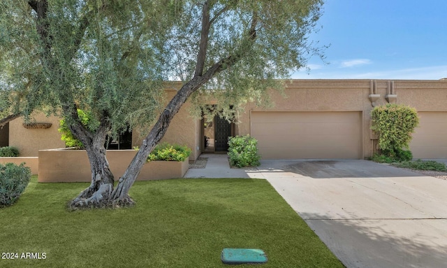 adobe home featuring a front yard and a garage