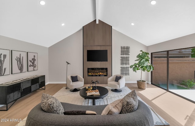 living room with lofted ceiling with beams, a fireplace, and light hardwood / wood-style floors