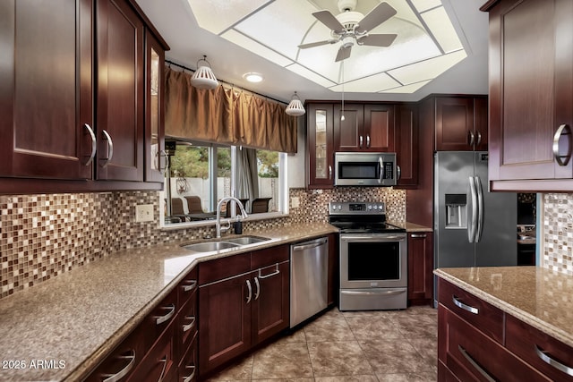 kitchen featuring sink, ceiling fan, appliances with stainless steel finishes, light stone countertops, and decorative backsplash