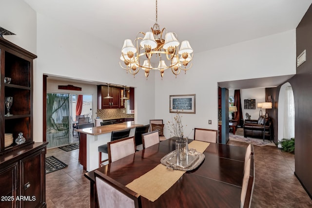 dining space featuring a towering ceiling, a chandelier, and dark tile patterned floors