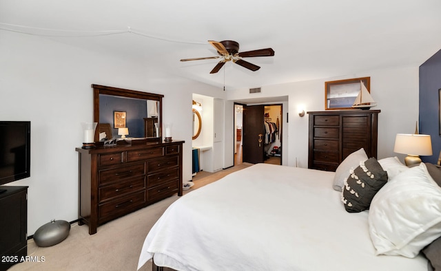 bedroom featuring connected bathroom, a spacious closet, light carpet, a closet, and ceiling fan