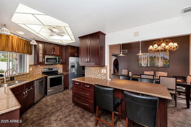 kitchen featuring tasteful backsplash, appliances with stainless steel finishes, sink, and ceiling fan with notable chandelier