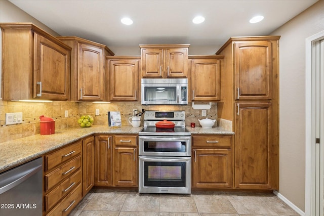 11320 E Newcastle Ave, Mesa, AZ 85209 - kitchen featuring stainless steel appliances, decorative backsplash, light stone counters, brown cabinetry, and recessed lighting