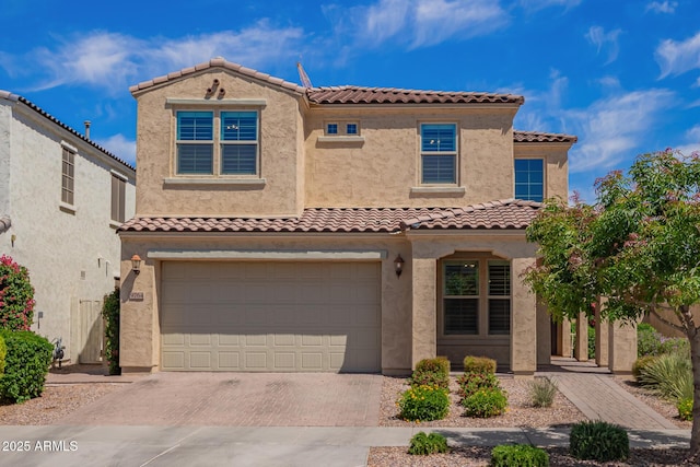 view of front facade with decorative driveway, an attached garage, stucco siding, and a tiled roof