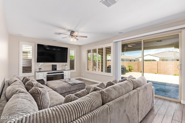 living area with ceiling fan, baseboards, and light wood finished floors