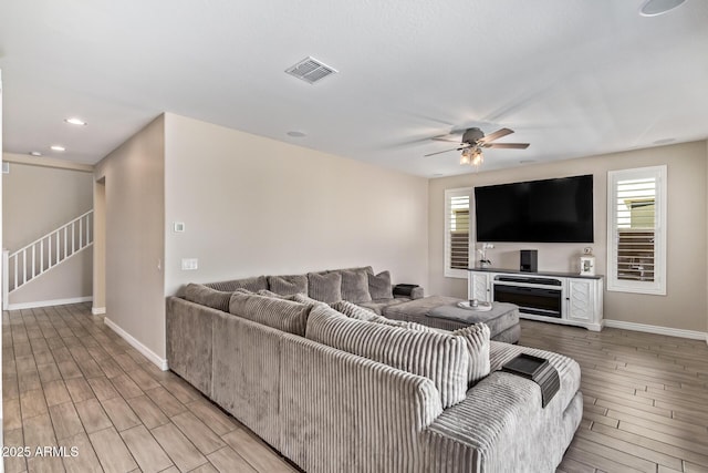 living room featuring wood tiled floors, stairway, baseboards, and recessed lighting