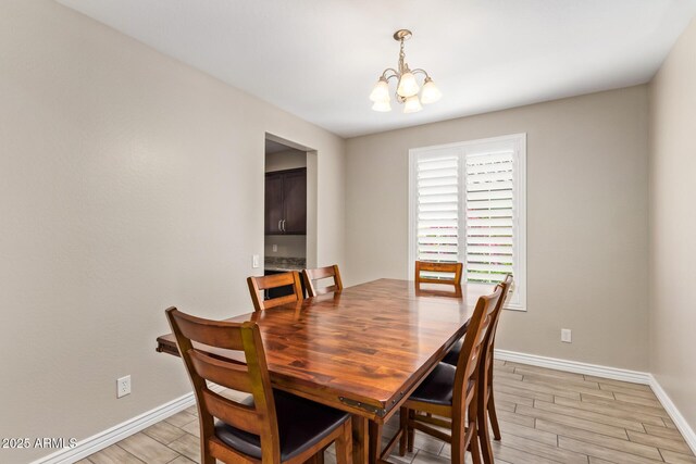 dining room featuring a chandelier, baseboards, and wood finish floors