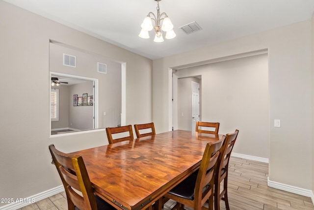 dining room with a chandelier, baseboards, and light wood-style floors