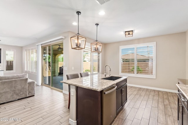 kitchen with a sink, wood finish floors, dishwasher, baseboards, and healthy amount of natural light