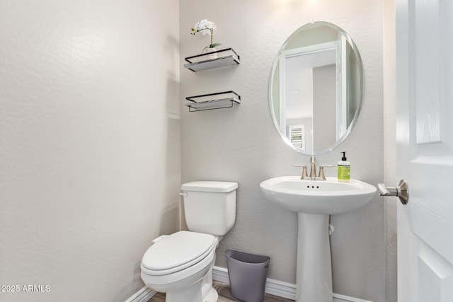 half bathroom with toilet and baseboards
