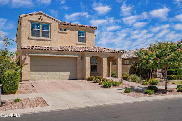 mediterranean / spanish house featuring decorative driveway, stucco siding, an attached garage, and a tiled roof