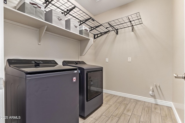 washroom with baseboards, separate washer and dryer, light wood finished floors, and bar area