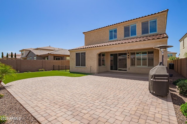 back of house featuring stucco siding, a fenced backyard, a patio area, and a tile roof